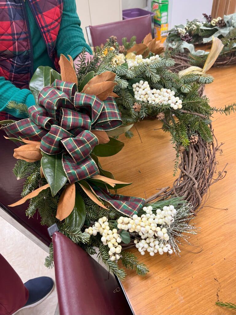 A wreath with pine branches and a plaid bow.