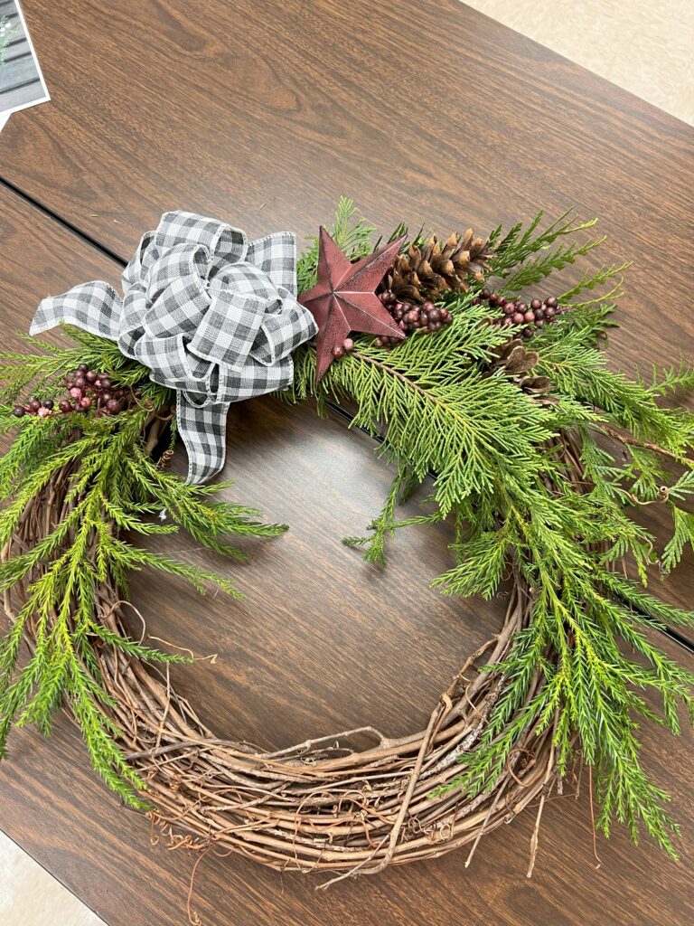 Completed wreath with an evergreen branch and ribbon.